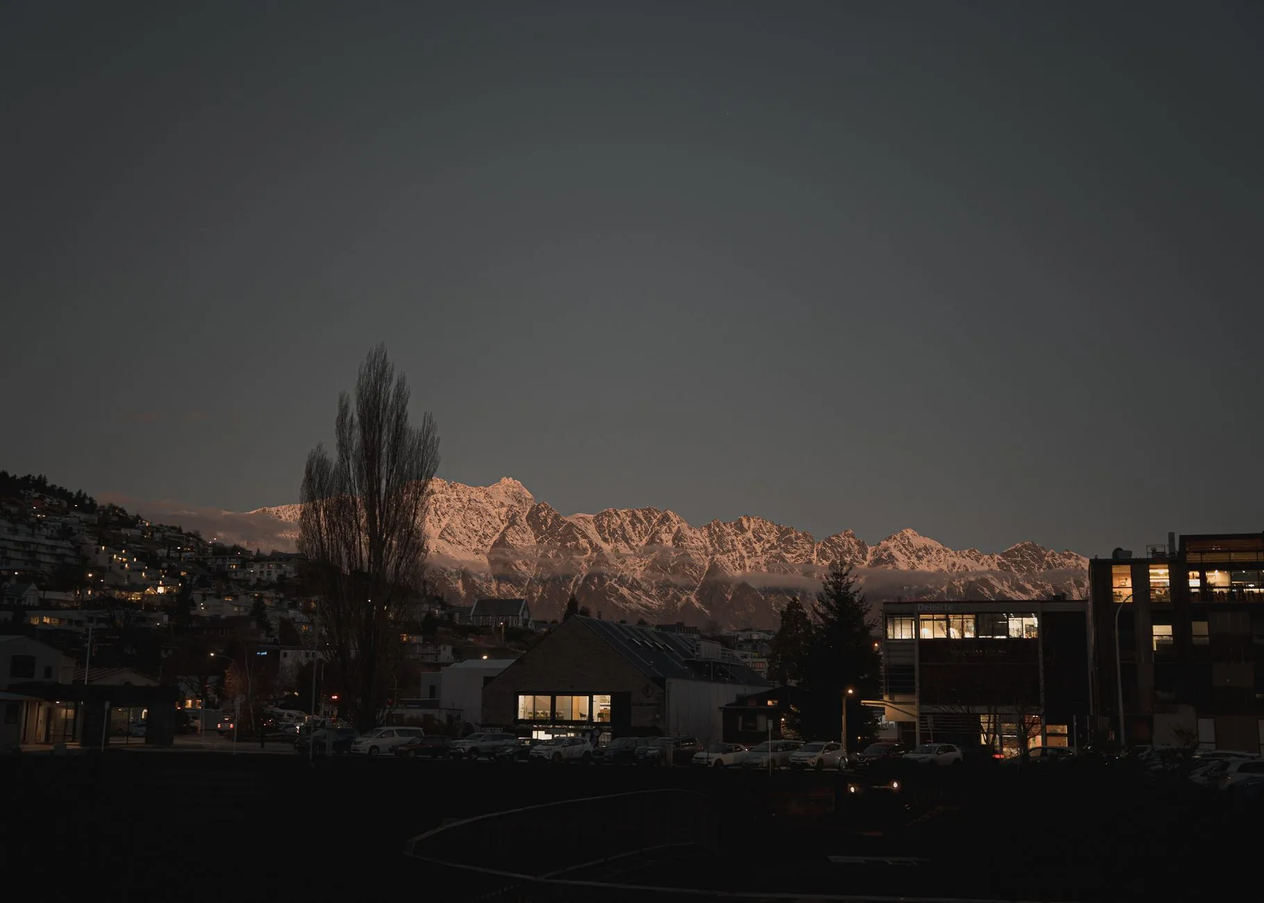 Mountain ridges catching the last light above a town at dusk