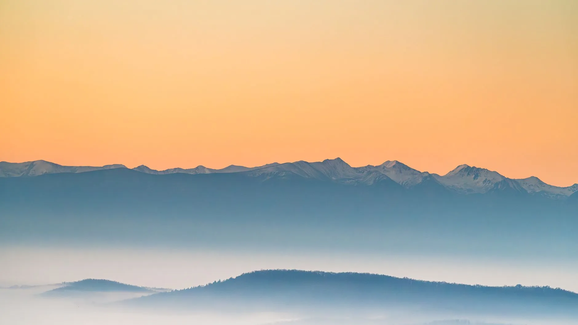 Snow-capped peaks above a sea of mist at sunrise