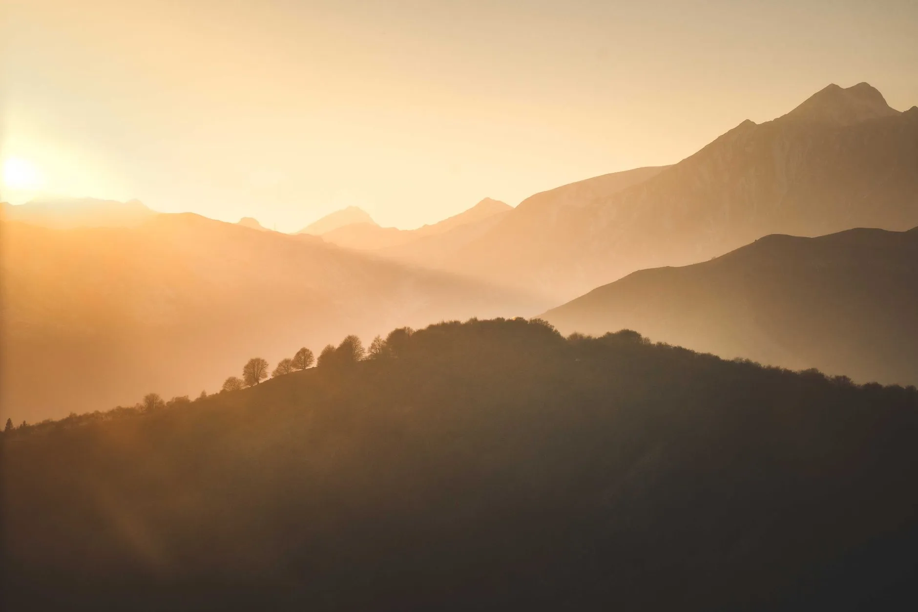Sunrise light spilling over layered mountain ridges